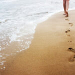 A young woman walking on the sand.